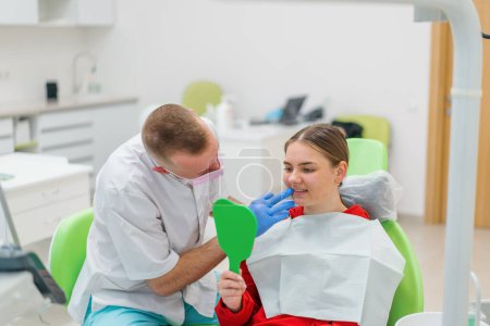 Foto de Mujer feliz mirando al espejo disfrutando de dientes limpios sanos hermosa sonrisa después del tratamiento clínica dental - Imagen libre de derechos