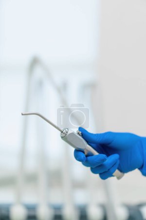 Téléchargez les photos : Le dentiste professionnel tient la seringue d'eau d'air d'outils de travail dans la main gantée avant que la clinique de procédure ferme - en image libre de droit