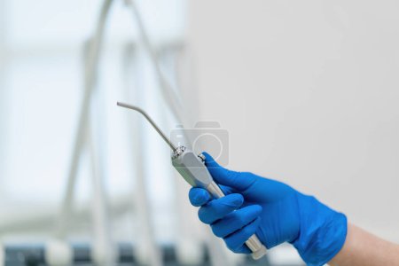 Photo for Professional dentist holds working tools air water syringe in gloved hand before procedure clinic close up - Royalty Free Image