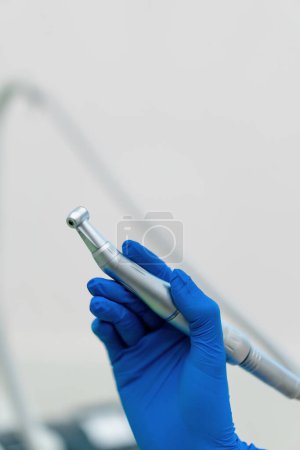 Foto de Odontólogo profesional que sostiene la herramienta de trabajo pieza de mano de turbina dental en la mano enguantada antes del procedimiento en la clínica de cerca - Imagen libre de derechos