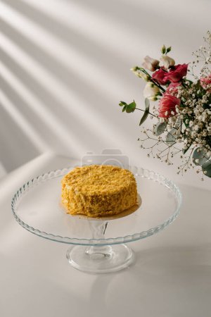 Téléchargez les photos : Délicieux gâteau napoléon pâte feuilletée fraîchement faite sur support en verre fond blanc avec concept de dessert fleurs - en image libre de droit