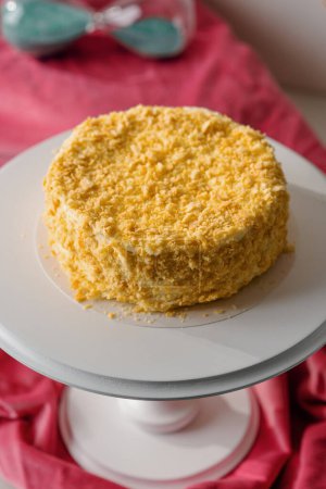 Téléchargez les photos : Délicieux gâteau napoléon feuilleté fraîchement préparé sur un stand blanc sur fond lumineux concept de dessert close-up - en image libre de droit