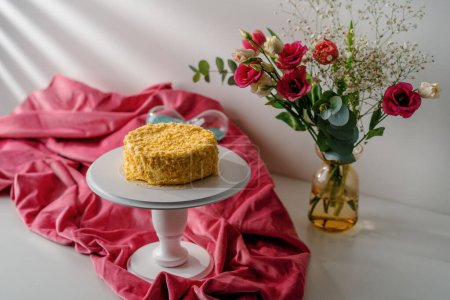 Téléchargez les photos : Délicieux gâteau Napoléon fraîchement préparé à partir de pâte feuilletée sur un stand blanc sur fond lumineux de fleurs concept de dessert - en image libre de droit