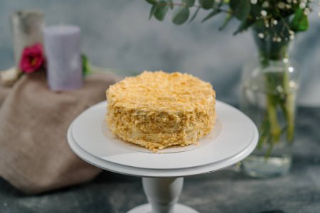 Téléchargez les photos : Délicieux gâteau napoléon feuilleté fraîchement fait sur un stand blanc sur fond de fleurs concept de dessert - en image libre de droit