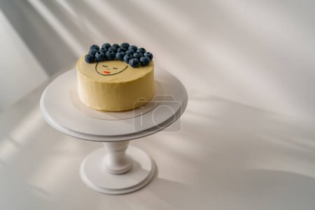 Photo for Delicious freshly made sponge cake bento, decorated with berries and a drawing stands on a stand on a white background - Royalty Free Image