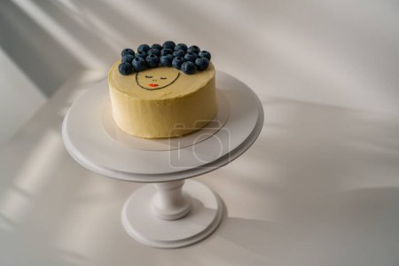 Foto de Delicioso pastel de esponja recién hecho bento, decorado con bayas y un dibujo se encuentra en un soporte sobre un fondo blanco - Imagen libre de derechos