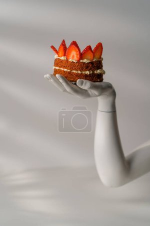 Photo for Piece of delicious freshly prepared Red velvet cake in hand decorated with butter cream frosting and strawberries - Royalty Free Image