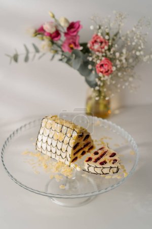 Photo for Delicious cherry cake  decorated with almond shavings on a stand cut out piece on white background with flowers - Royalty Free Image
