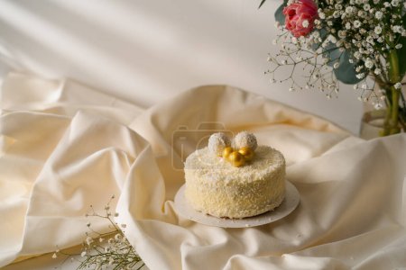 Téléchargez les photos : Délicieux gâteau éponge à la crème fraîchement fait décoré avec des bonbons de copeaux de noix de coco sur fond de fleurs - en image libre de droit