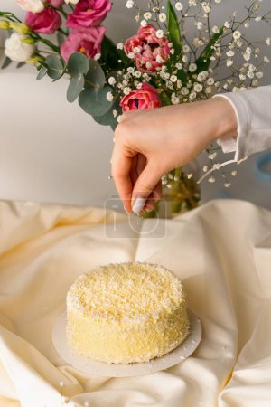 Photo for Delicious freshly made sponge cake sprinkled with coconut shavings on background of flowers dessert cooking concept - Royalty Free Image