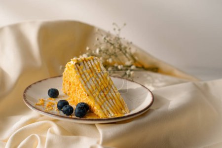 Foto de Delicioso pedazo de pastel de miel recién hecho rociado con miel en un plato con bayas sobre fondo beige concepto de postre - Imagen libre de derechos