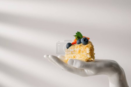 Téléchargez les photos : Morceau de pâte feuilletée délicieuse fraîchement faite gâteau Napoléon avec des fraises et des baies sur un fond blanc sur pied à la main - en image libre de droit