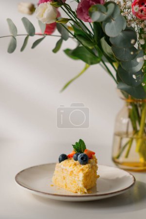 Foto de Pedazo de pastel de hojaldre recién hecho Napoleón con fresas y bayas sobre fondo blanco con flores - Imagen libre de derechos