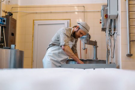 Foto de Fabricante de queso en uniforme hace que el queso pone moldes para verter el proceso de producción de queso pequeña empresa y el espíritu empresarial - Imagen libre de derechos