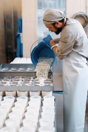 Foto de Fabricante de queso vierte queso fresco en moldes de fabricación de queso brie producción de queso artesanal - Imagen libre de derechos