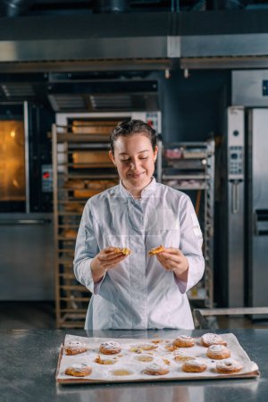 Téléchargez les photos : Belle femme boulanger larmes prêt fraîchement cuit chaud pains aromatiques vérifie la production de pâte boulangerie - en image libre de droit