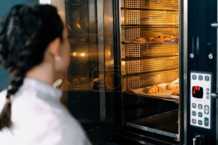 Téléchargez les photos : Attrayant boulanger prend brioches prêtes et croissants professionnel four boulangerie production produits de boulangerie frais - en image libre de droit