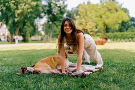 Téléchargez les photos : Jeune belle fille faire yo en plein air dans le parc avec peu de graisse pelucheux chien corgi animal en plein air - en image libre de droit