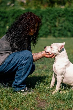 Téléchargez les photos : Psychologue chien calme un chien blanc d'une grande race de pit-bull dans le parc un animal de compagnie avec une langue saillante stressé - en image libre de droit