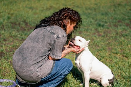 Téléchargez les photos : Psychologue chien calme un chien blanc d'une grande race de pit-bull dans le parc un animal de compagnie avec une langue saillante stressé - en image libre de droit