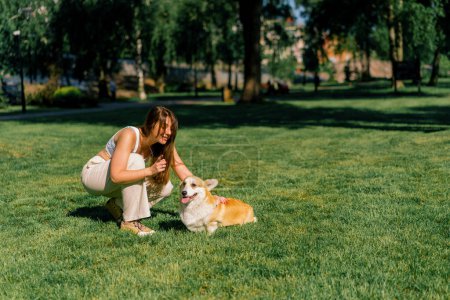 Foto de Un psicólogo perro regaña a un lindo corgi que no obedece en el parque el propietario habla con el perro en un paseo verano animales de la naturaleza - Imagen libre de derechos