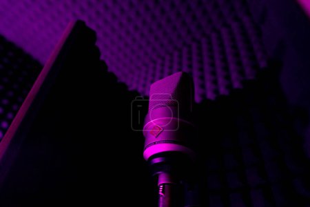 Foto de Equipo de estudio de grabación profesional para grabar un micrófono de canción en stand close-up luz de neón púrpura - Imagen libre de derechos