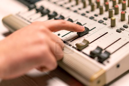 Photo for Professional recording studio sound engineer with finger adjusts volume level mixing console equalizer making music close-up - Royalty Free Image