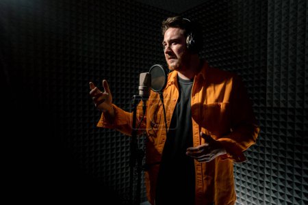Photo for Young pop rap artist emotionally recording new song professional recording studio singing with microphone - Royalty Free Image