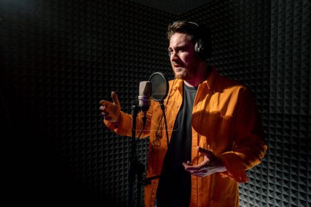 Photo for Young pop rap artist emotionally recording new song professional recording studio singing with microphone - Royalty Free Image