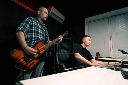 Foto de Intérprete de rock con grabación de guitarra eléctrica estudio de grabación tocando propia pista con ingeniero de sonido crear canción - Imagen libre de derechos