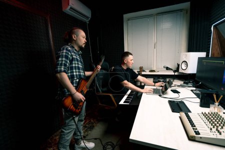 Foto de Intérprete de rock con grabación de guitarra eléctrica estudio de grabación tocando propia pista con ingeniero de sonido crear canción - Imagen libre de derechos