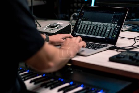 professioneller Tontechniker im Tonstudio passt den Lautstärkepegel am Mischpult-Equalizer an, der Musik-Laptop erzeugt