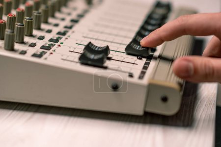 Foto de Ingeniero de sonido profesional del estudio de grabación con el dedo ajusta el ecualizador de la consola de mezcla de nivel de volumen haciendo música de cerca - Imagen libre de derechos