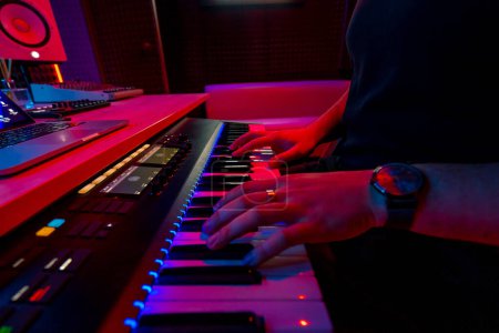 Foto de Estudio de grabación profesional ingeniero de sonido productor de música músico presionando teclas de sintetizador rojo luz de neón - Imagen libre de derechos