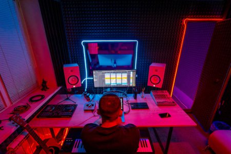 Photo for Professional sound recording studio sound engineer or music producer sitting at the console on audio track screen neon light - Royalty Free Image