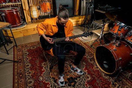Téléchargez les photos : Portrait de jeune artiste rock avec guitare électrique en studio d'enregistrement jouant sa propre piste instrument de musique batterie arrière-plan - en image libre de droit