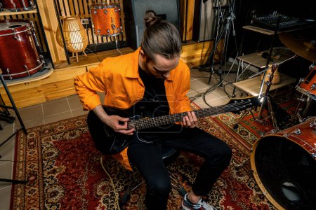 Photo for Portrait of young rock artist with electric guitar in recording studio playing own track musical instrument drums background - Royalty Free Image
