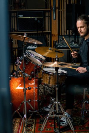 Photo for A young male drummer plays a drum kit in a recording studio at a professional musician's rehearsal recording song - Royalty Free Image