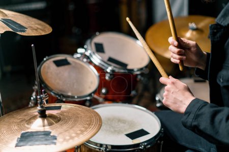 Photo for Drummer plays a drum kit in a recording studio at a professional musician rehearsal recording a song beats the sticks on the instrument closeup - Royalty Free Image