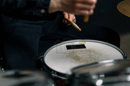 Photo for Drummer plays a drum kit in a recording studio at a professional musician rehearsal recording a song beats the sticks on the instrument closeup - Royalty Free Image