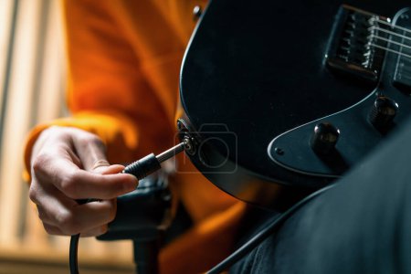 Foto de Intérprete de rock con guitarra eléctrica en estudio de grabación sostiene instrumento musical en las manos conecta con cable de cuerda - Imagen libre de derechos