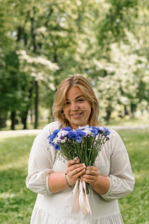 Photo for Portrait of a beautiful young pregnant woman with a bouquet of flowers in her hands smiling and rejoicing at presented bouquet - Royalty Free Image