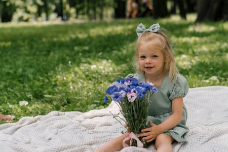 Photo for Portrait of a happy little girl resting in park with flowers carefree childhood summer day outdoor recreation - Royalty Free Image