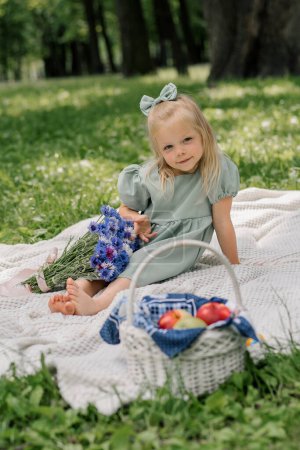 Téléchargez les photos : Portrait d'une petite fille heureuse reposant dans le parc avec des fleurs sans soucis enfance journée d'été loisirs en plein air - en image libre de droit