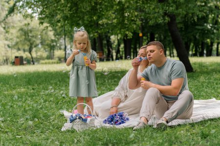 Foto de Feliz familia relajante al aire libre en el parque papá y su hija soplando burbujas de jabón divertido fin de semana familiar infancia sin preocupaciones - Imagen libre de derechos