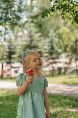 Foto de Niña linda en vestido de verano verde comiendo delicioso helado Niño con helado ciudad parque verano familia estilo de vida Infancia - Imagen libre de derechos