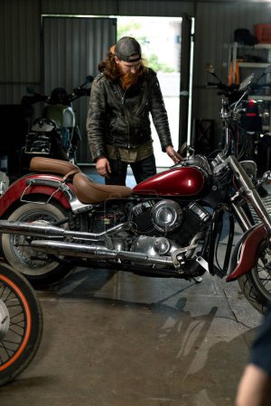 Téléchargez les photos : Atelier de moto créatif authentique Garage barbu mécanicien motard entre dans les locaux avant de commencer le travail - en image libre de droit