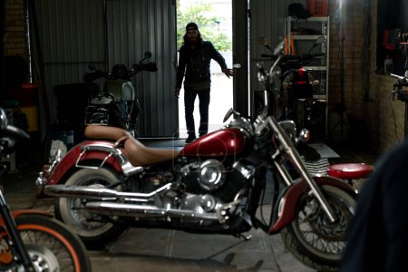 Photo for Creative authentic motorcycle workshop Garage bearded biker mechanic enters the premises before starting work - Royalty Free Image