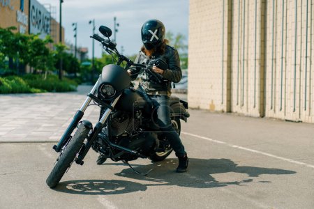 Foto de Brutal motorista pelirrojo en un casco se sienta en una motocicleta negra antes del inicio de la carrera la lujuria por el concepto de deporte motor de velocidad - Imagen libre de derechos