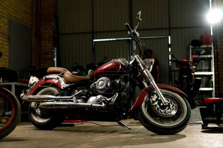 Téléchargez les photos : Atelier de moto authentique une belle moto moderne se tient dans le garage avant réparation - en image libre de droit